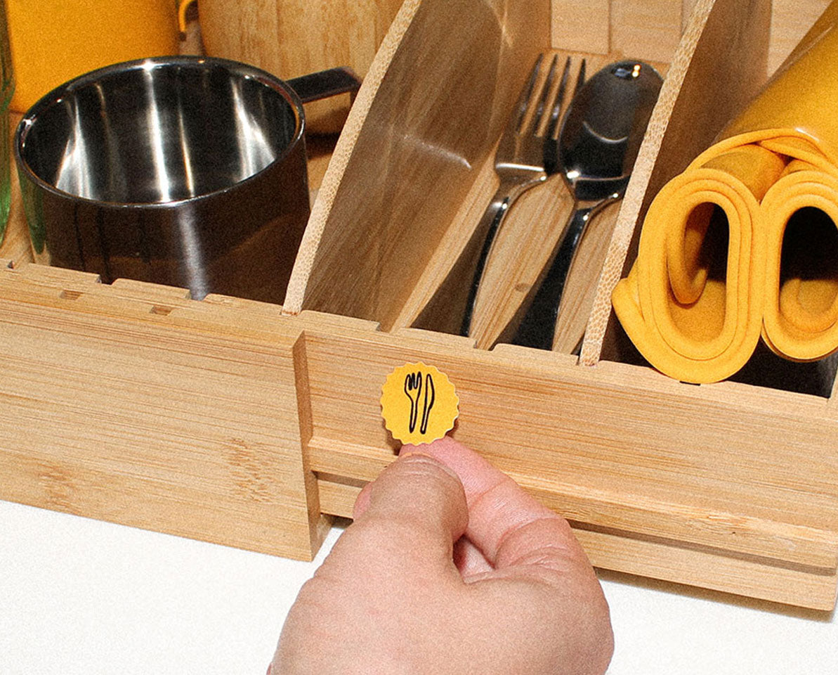 Child organising utensils in Montessori storage system